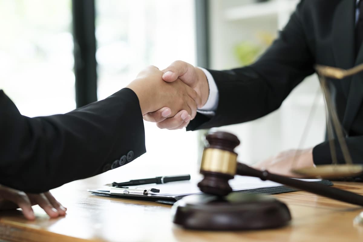 Businessman Shaking hands with Professional male lawyer after discussing good deal of contract in courtroom, Concepts of law, Judge gavel with scales of justic, Legal services advice at the law office.